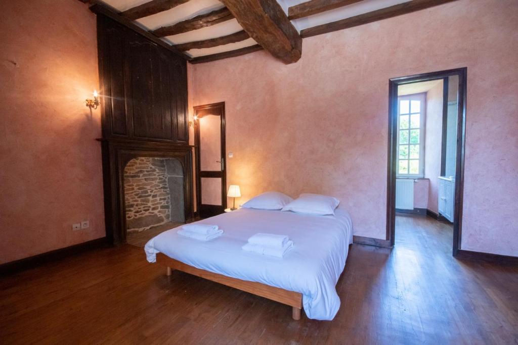 a bedroom with a bed in a room with a fireplace at Manoir le Cosquer in Pommerit-le-Vicomte