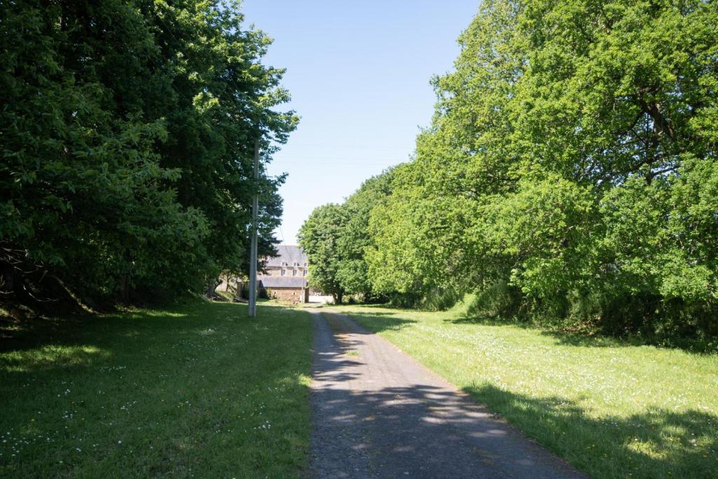 a path with trees on the side of a field at Manoir le Cosquer in Pommerit-le-Vicomte