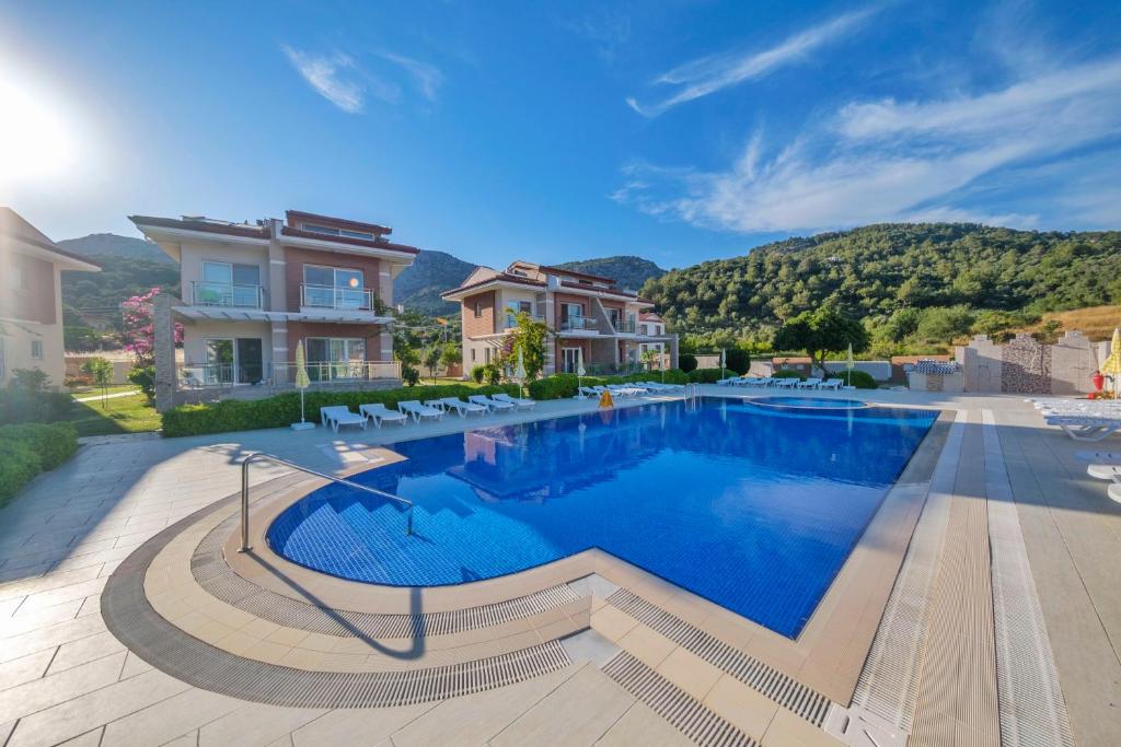 a swimming pool in a villa with mountains in the background at Golden Golf Sarıgerme Villaları in Sarigerme