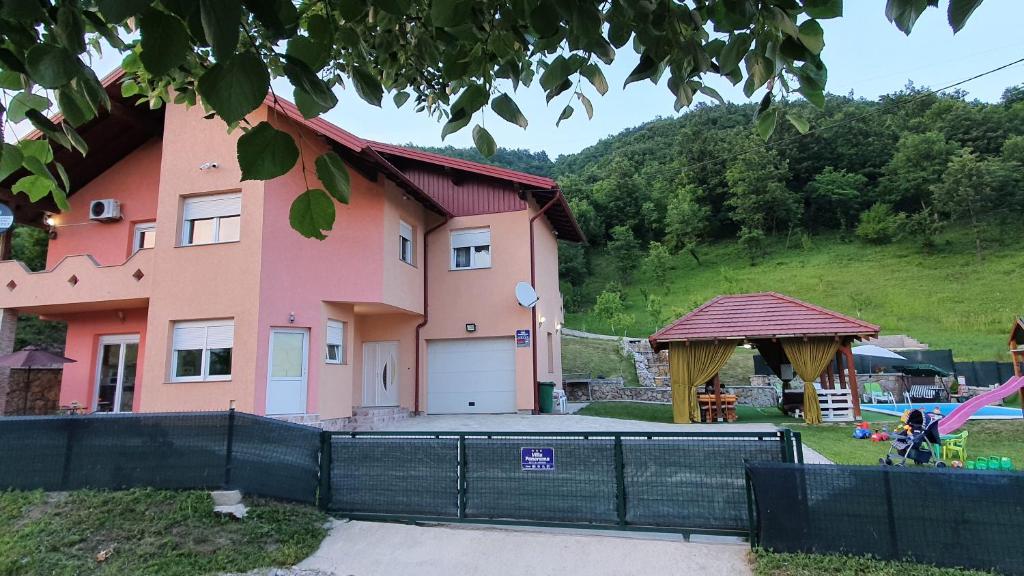 ein rosa Haus mit einem Zaun davor in der Unterkunft Villa Panorama in Bihać