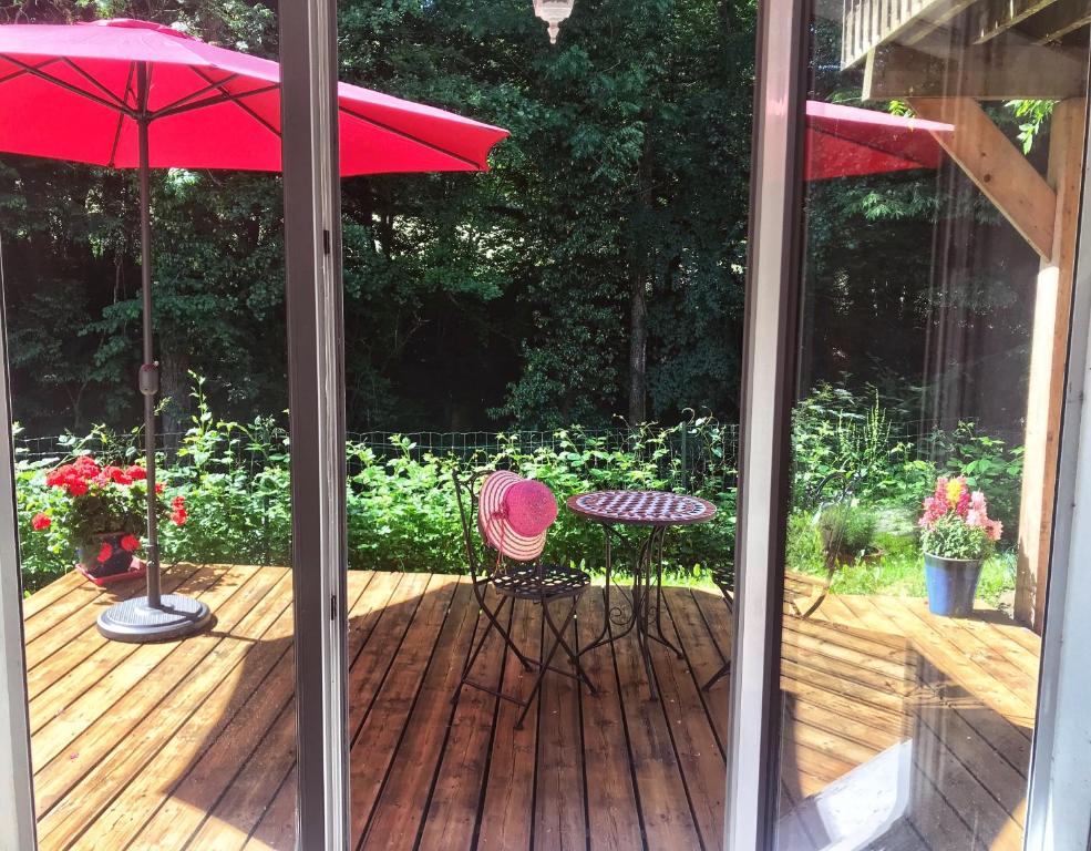 une terrasse avec une table, des chaises et un parasol dans l'établissement Appartement au calme avec terrasse verdoyante entre Annecy et Genève, à Villy-le-Pelloux