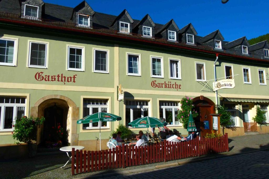 un grand bâtiment avec des personnes assises à l'extérieur dans l'établissement Hotel & Gasthof Garküche, à Leutenberg