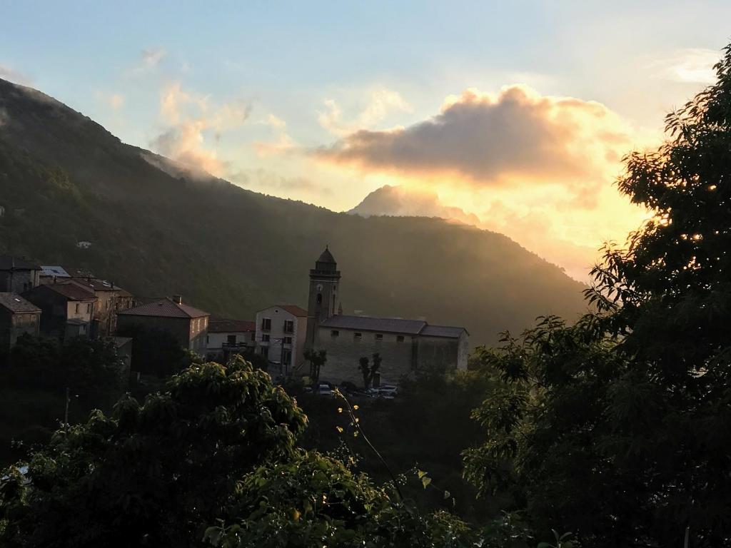 a town with a clock tower and a mountain at MAISON VILLAGE MARIGNANA in Marignana