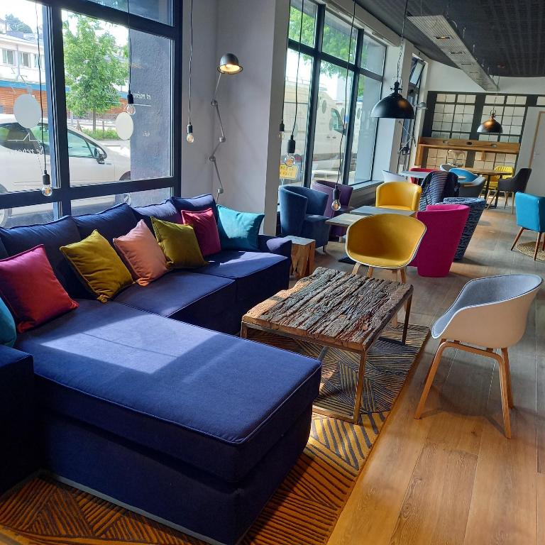 a living room with a blue couch and a table at Campanile Epinal Centre - Gare in Épinal