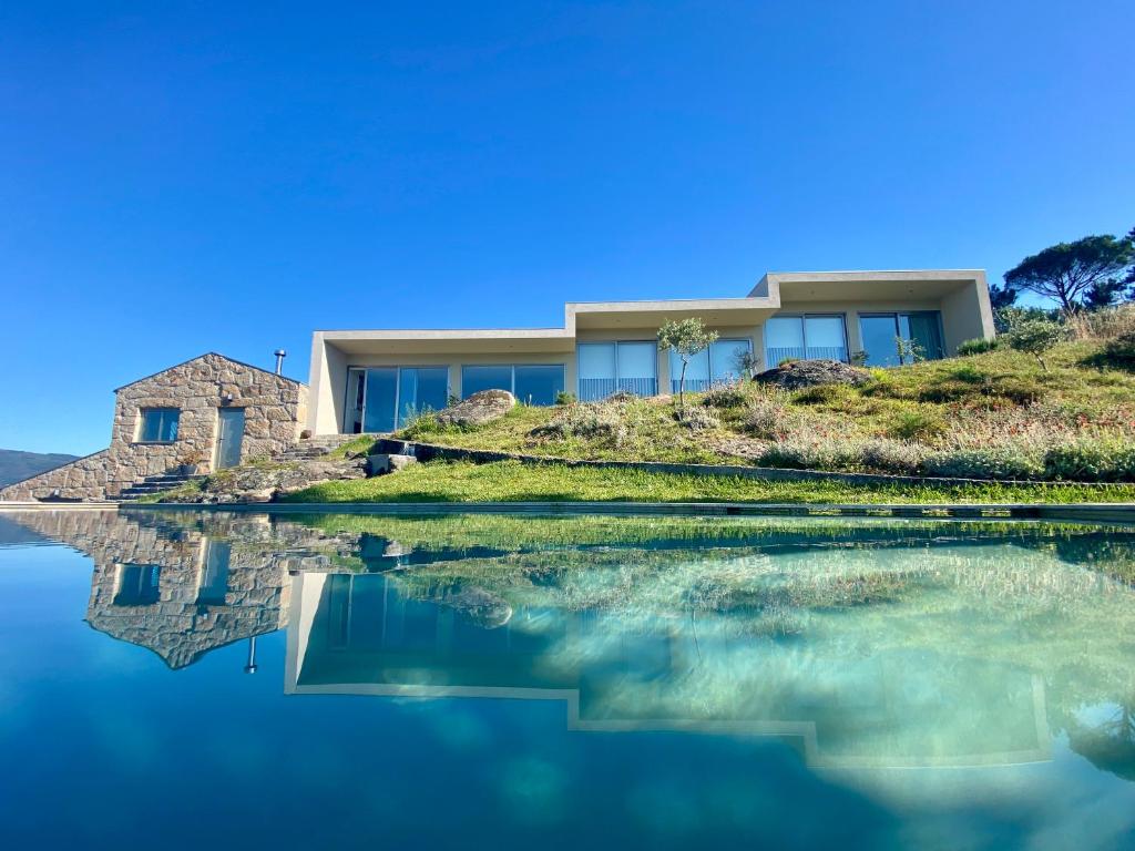 a house on a hill next to a body of water at Casa do Vale de Cerdeiras in Ancede