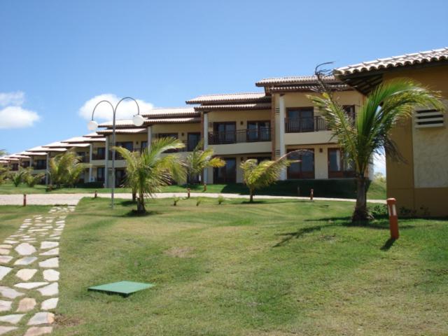 a building with palm trees in front of a building at Condomínio Encantador Piscina e Praia E12 in Zumbi