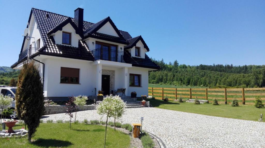 uma casa branca com um telhado preto em Lawendowy Dworek em Laskówka