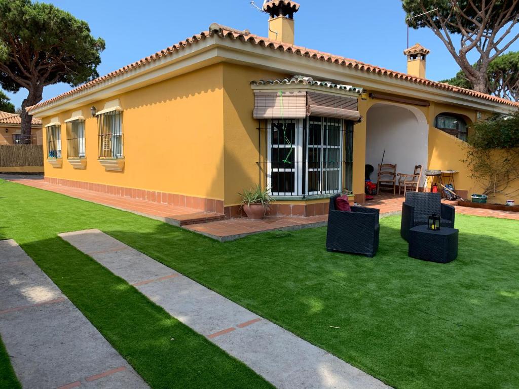 a yellow house with a lawn in front of it at Chiclana casa maría in Chiclana de la Frontera