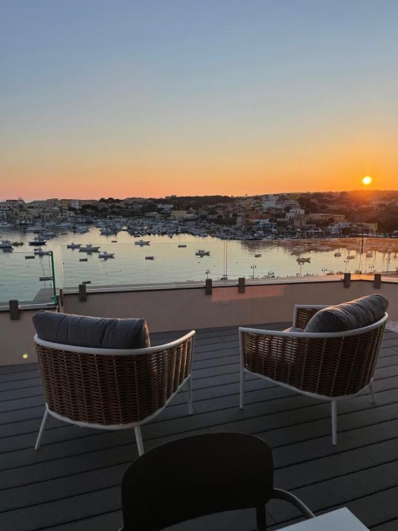 duas cadeiras num telhado com o pôr-do-sol ao fundo em B&B Giro Di Boa em Lampedusa