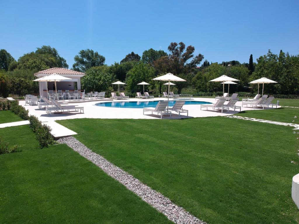 a pool with chairs and umbrellas on a lawn at Santos Apartments & Studios in Dassia