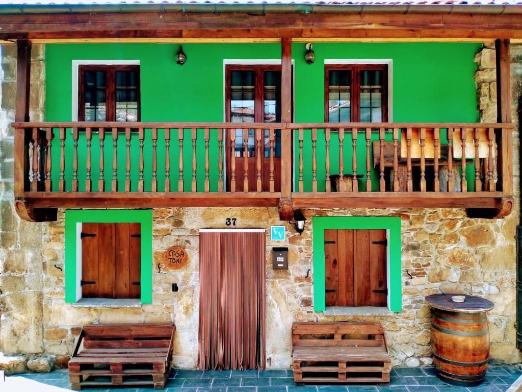 a green building with wooden doors and a balcony at Casa con encanto in Aller