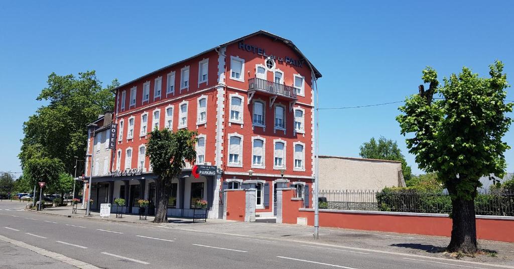 a large red building on the side of a street at Hotel de La Paix in Oloron-Sainte-Marie