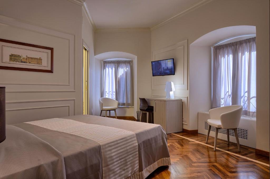 Pokój hotelowy z łóżkiem, biurkiem i krzesłami w obiekcie Polinari Rooms San Pietro Roma w Rzymie