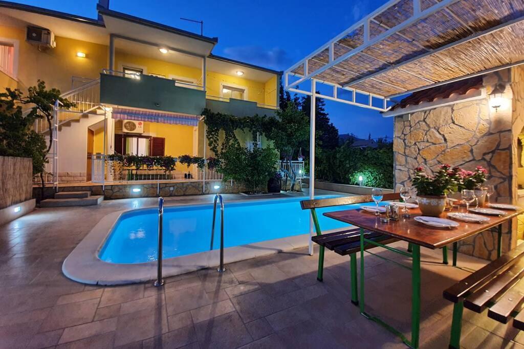 a patio with a table and a swimming pool at Beautiful villa - private heated pool, parking, BBQ near Split in Solin