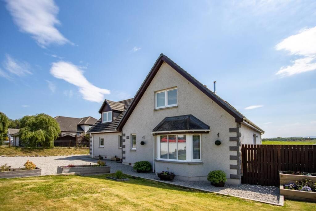 una casa blanca con una valla y un patio en Gleneden House, en Tore