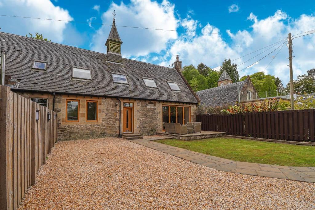 una vieja casa de piedra con una valla y un patio en Fantastic Cottage in Loch Lomond National Park, en Alexandria