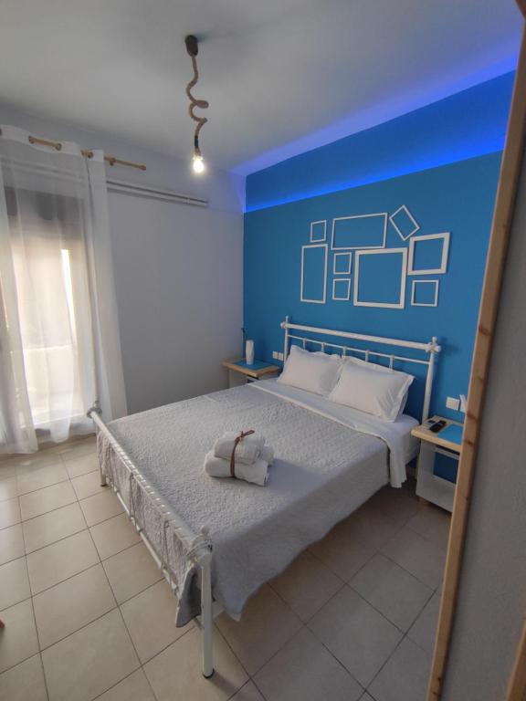 a bedroom with a bed with a blue wall at Poseidon Rooms in Kala Nera