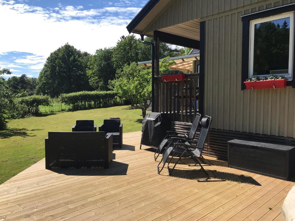 a wooden deck with chairs and a house at Haere Mai B&B Orust in Henån