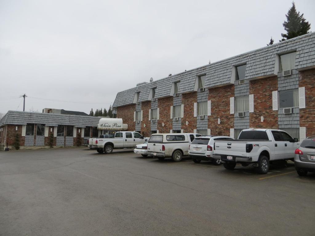 a parking lot with cars parked in front of a building at Twin Pine Inn & Suites in Hinton