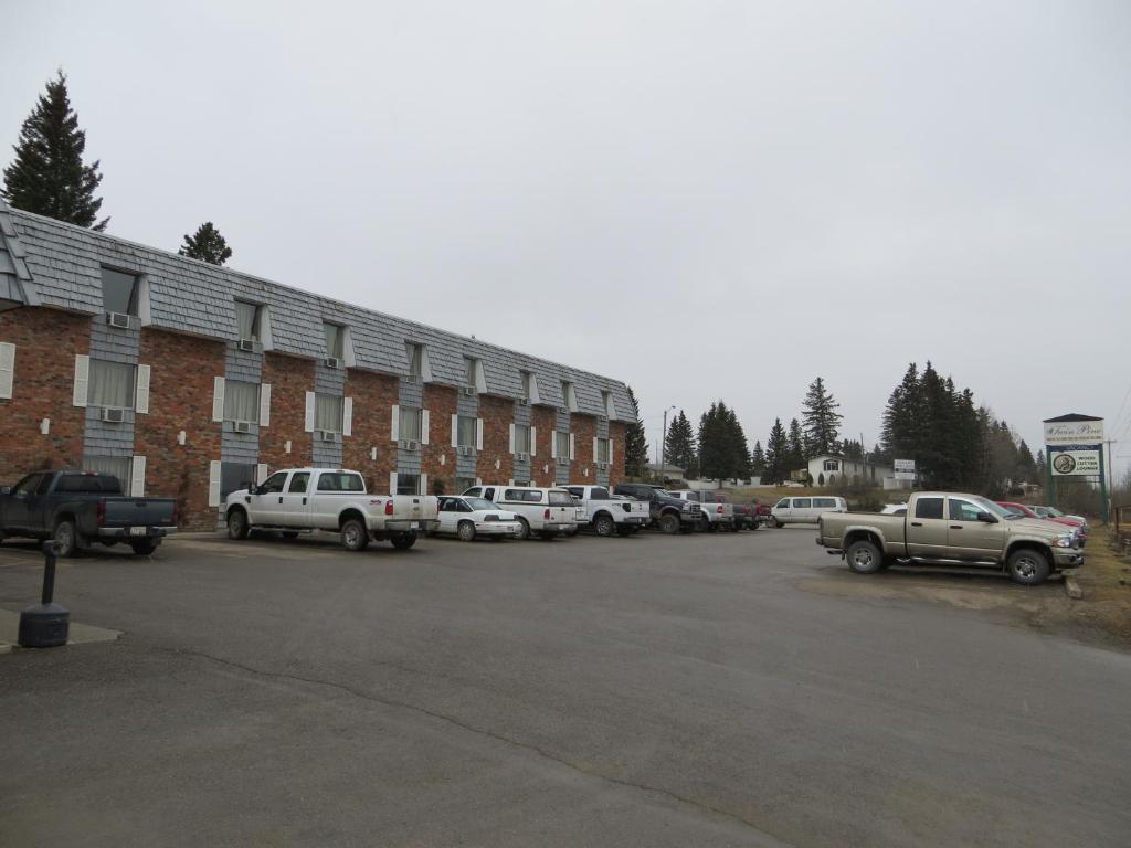 a parking lot with cars parked in front of a building at Twin Pine Inn & Suites in Hinton