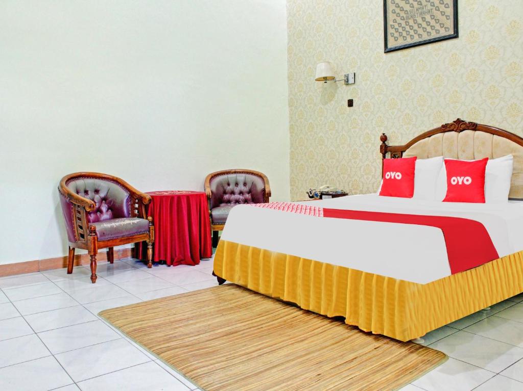 a bedroom with a large bed and two chairs at Capital O 90417 Hotel Batu Suli Internasional in Palangkaraya