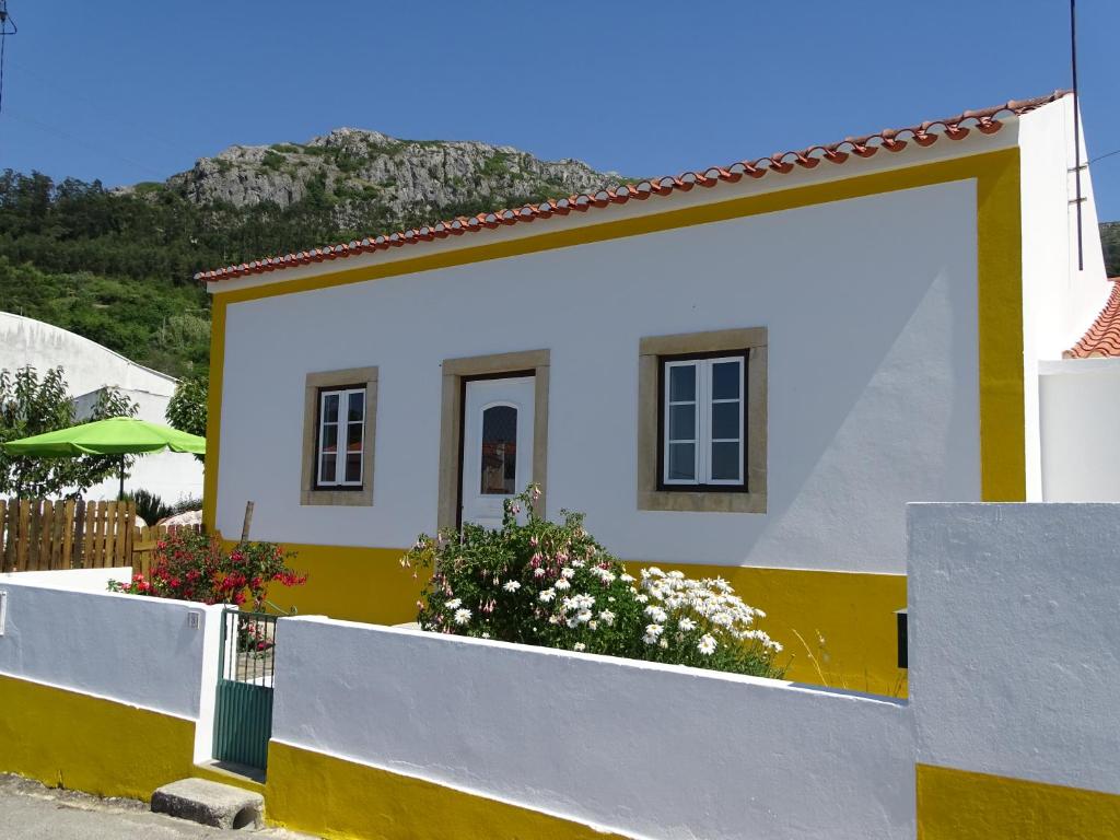 una casa blanca y amarilla con una valla en Casa Do Avô In Montejunto, en Cadaval