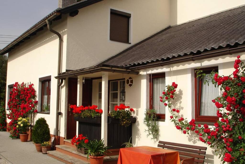 una casa bianca con fiori rossi sul davanti di Villa Lindwurm a Klagenfurt