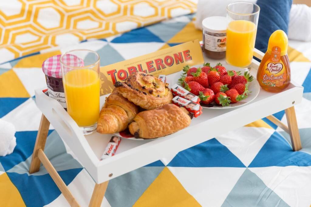 a table with a tray of breakfast foods and orange juice at DÉPLACEMENT PRO &amp; TOURISME - NETFLIX - WIFI - Easy CHECK-IN in Bourg-la-Reine