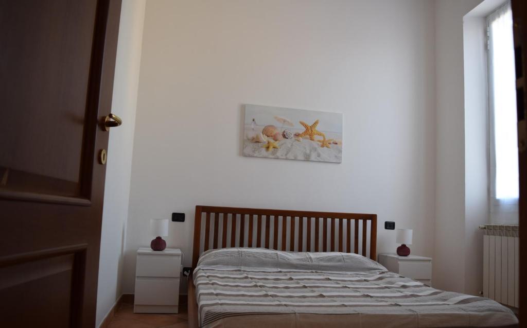 uma cama num quarto branco com uma fotografia na parede em Casa Ligure Ristrutturata 80m2 em Diano Marina