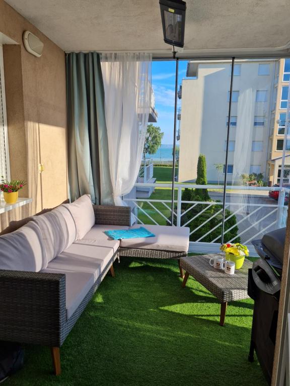 a living room with a couch and a balcony at EDA Beach Apartman in Siófok