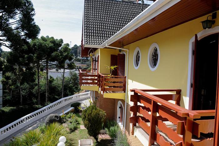 a yellow house with a porch and a balcony at Pousada da Lua in Campos do Jordão