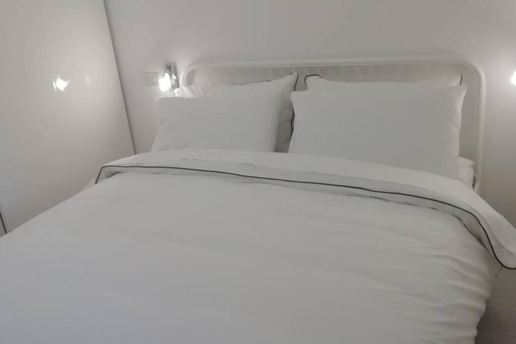 un letto bianco con lenzuola e cuscini bianchi di Appartamento Residence Castel Carlotta a Levico Terme