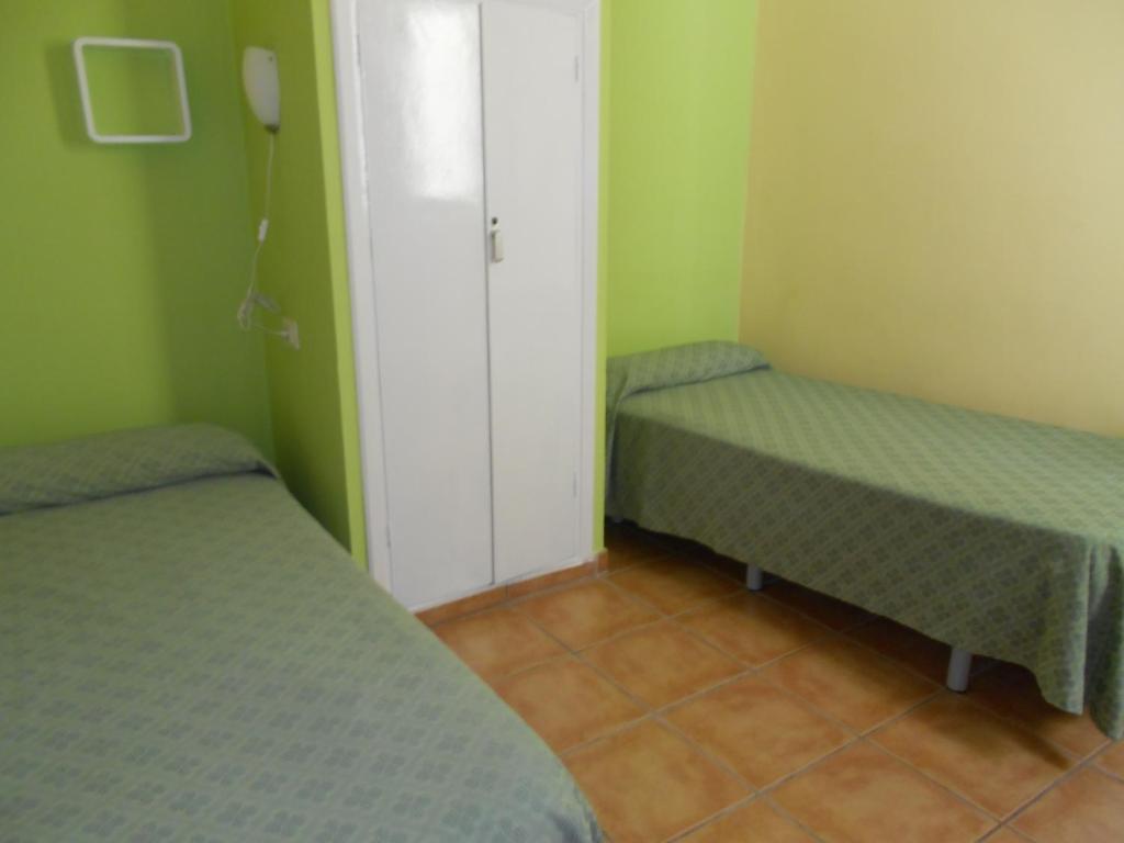 two beds in a small room with green walls at Pensión Mova in Santa Cruz de Tenerife