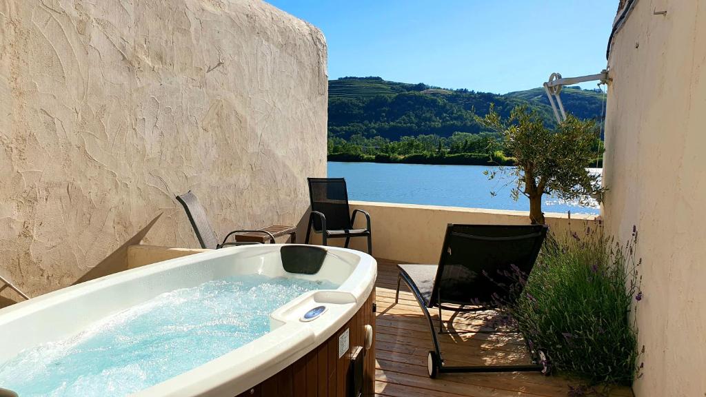 bañera en una terraza con vistas al lago en Maison jacuzzi, hammam et sauna, en Saint-Vallier