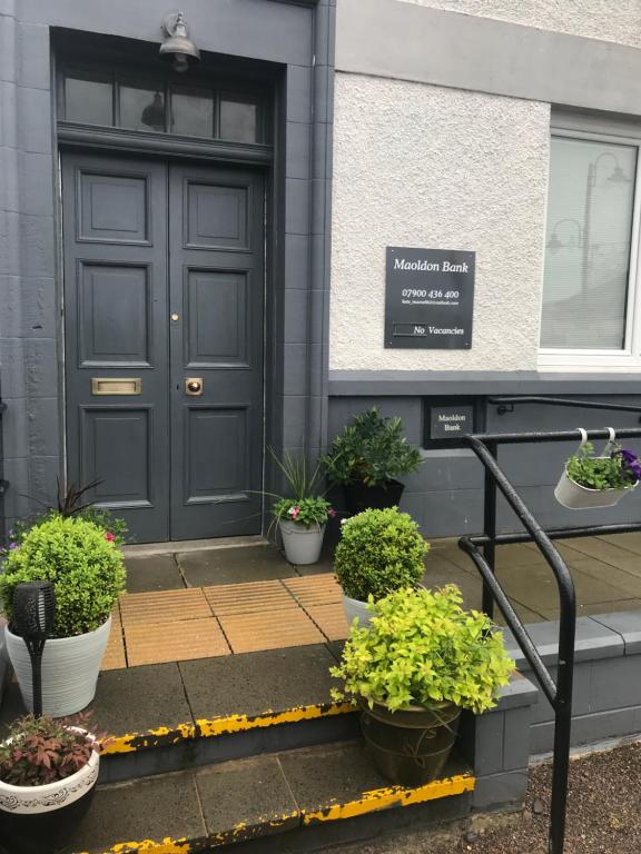 een voordeur van een gebouw met potplanten op de trappen bij Maoldon Bank in Mallaig