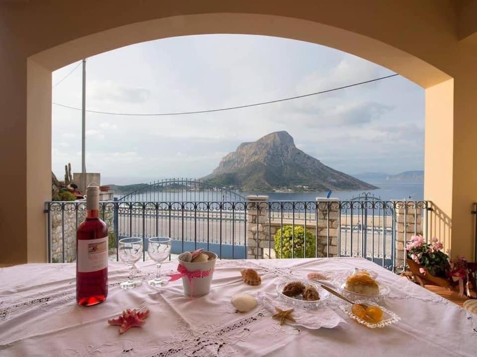 uma mesa com uma garrafa de vinho e vista para uma montanha em VILLA NEXT TO THE SEA!! em Calímnos