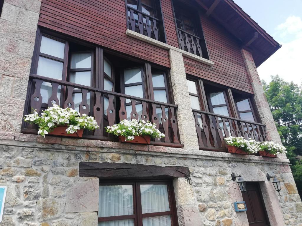a building with windows and flowers on a balcony at La Quintana de Doña Leonor in Arriondas