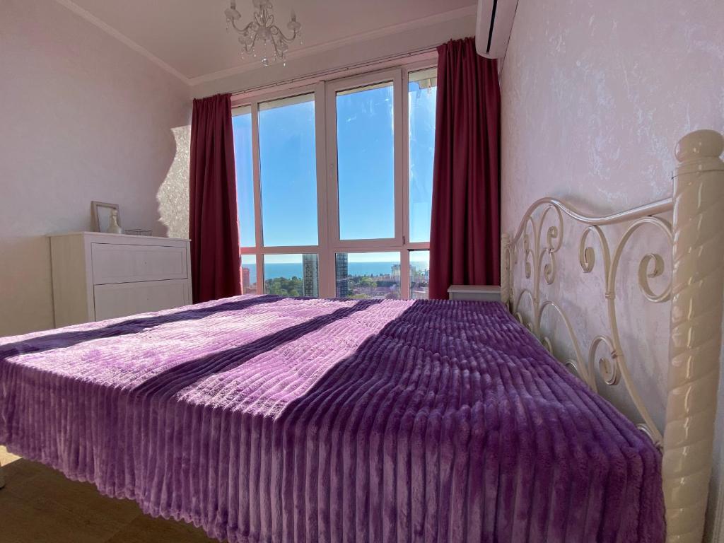 ソチにあるКвартира с 2 спальнями и видом на мореのベッドルーム(紫色のベッド1台、大きな窓付)