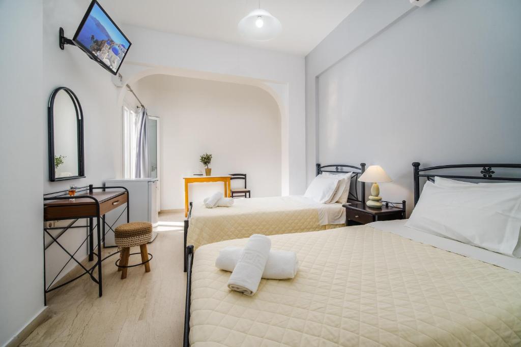 a bedroom with two beds and a desk and a mirror at Emmanouela Studios & Villas in Karterados