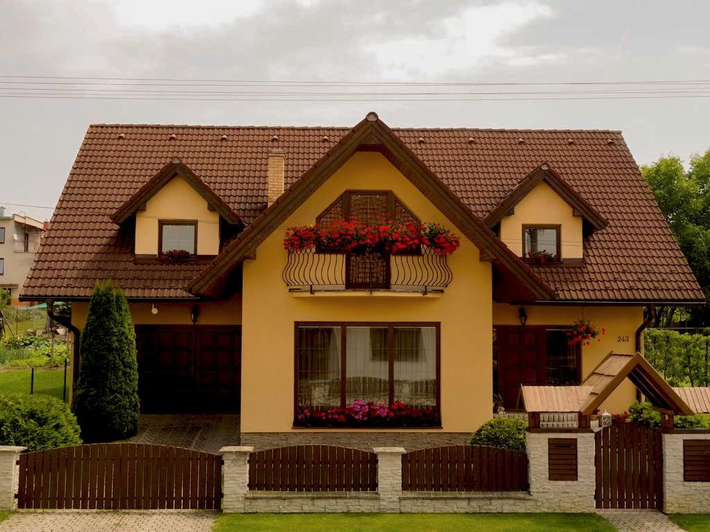 une maison jaune avec des fleurs dans une fenêtre dans l'établissement Penzion Farkys, à Jamník