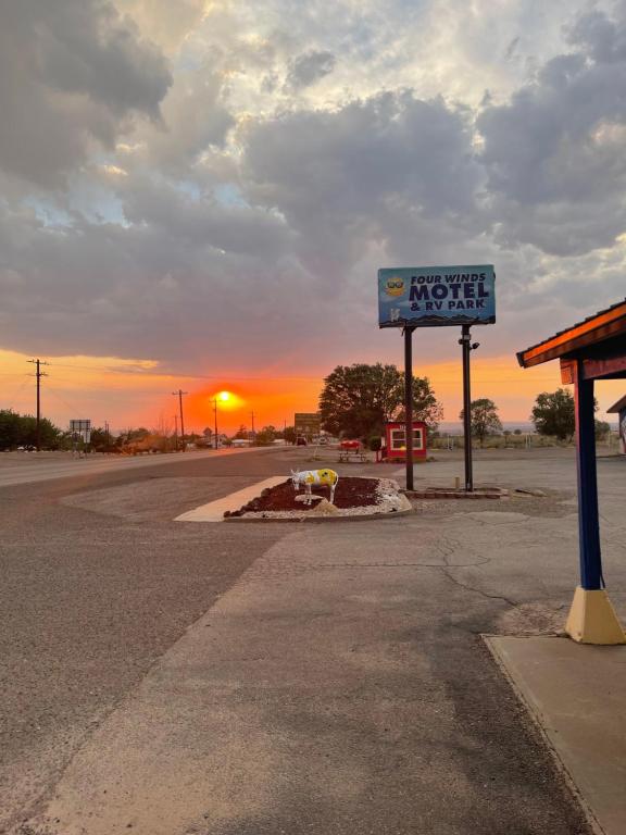 ein Schild für eine Tankstelle mit Sonnenuntergang im Hintergrund in der Unterkunft Four Winds Motel & RV Park in Carrizozo