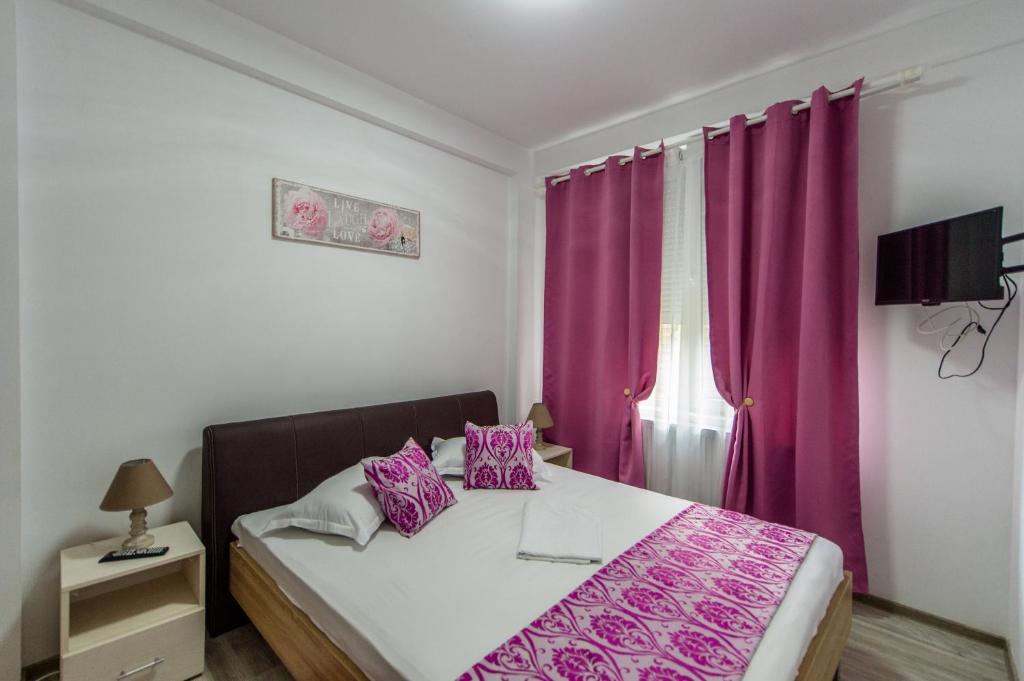 a bedroom with a bed with purple sheets and a window at Apartament Nacis in Mamaia Sat/Năvodari