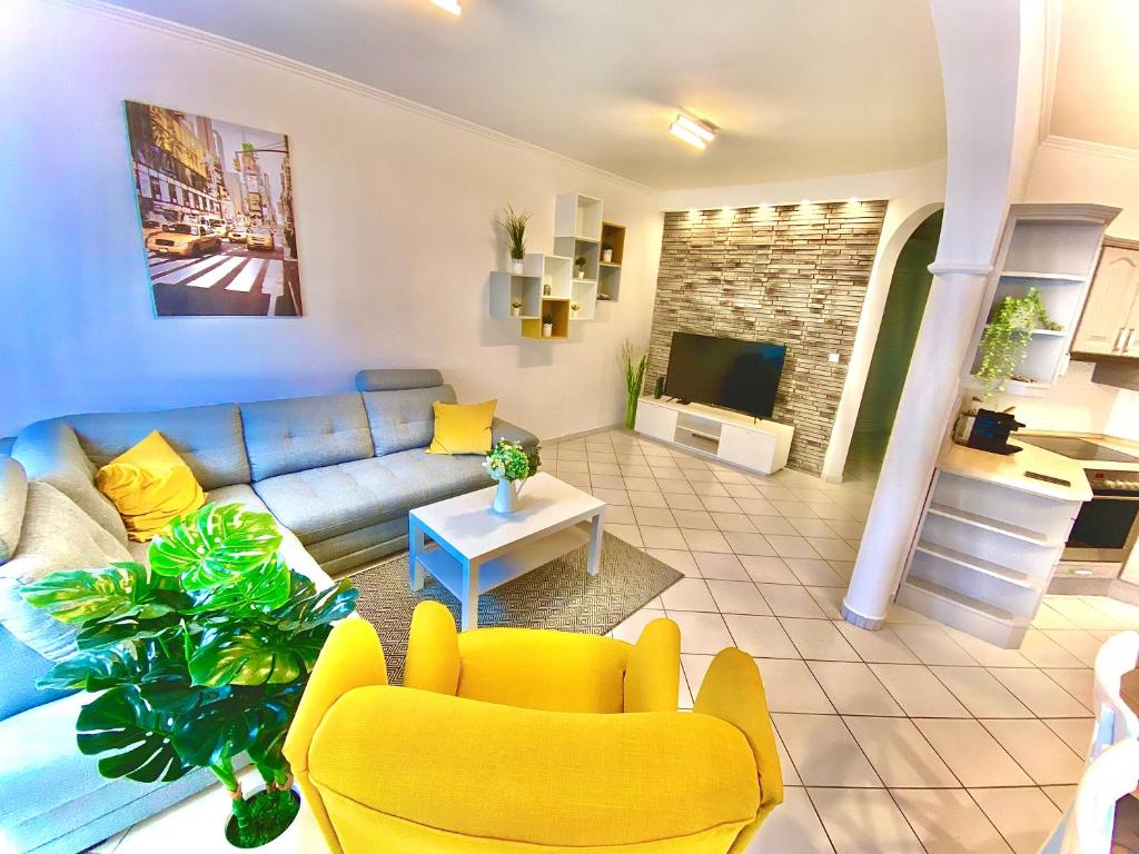 ein Wohnzimmer mit einem blauen Sofa und gelben Stühlen in der Unterkunft Mirell Apartman in Szeged