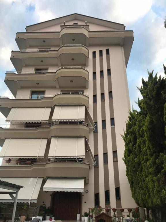 um edifício branco alto com uma árvore em frente em Guest House Il Palazzo em Durrës