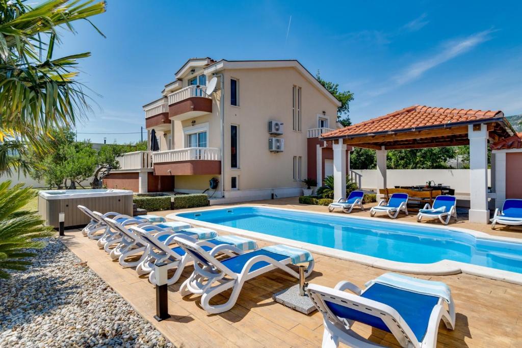 a villa with a swimming pool and lounge chairs at Villa Suker - Jacuzzi, Pool, Sauna in Kaštela