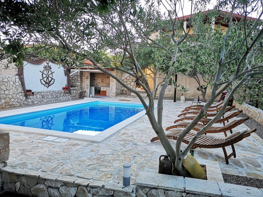 una piscina con sillas y un árbol al lado en Apartman Magas with private pool, en Vinjerac