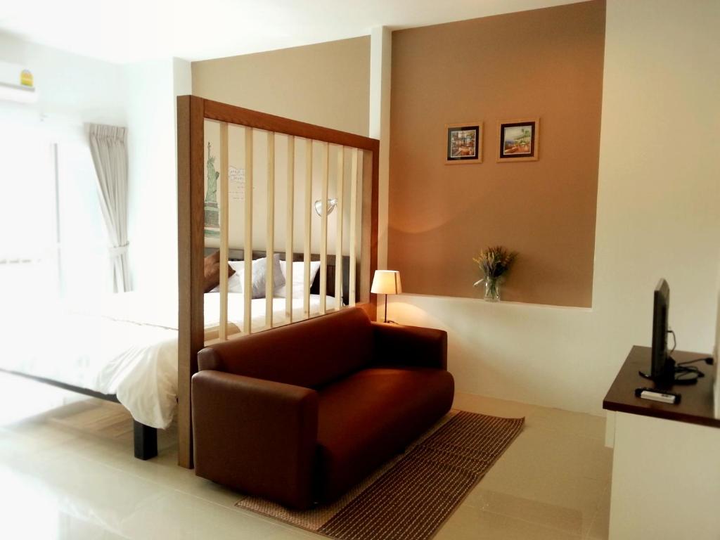 A bright room with a bed, sofa and television arranged across separate zones.