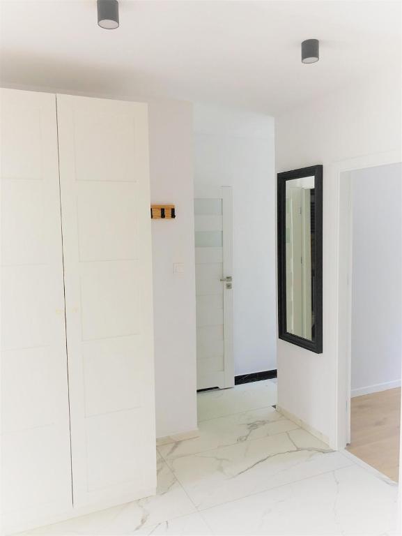 een kamer met witte kasten en een spiegel bij Sztormowa Apartment in Gdańsk