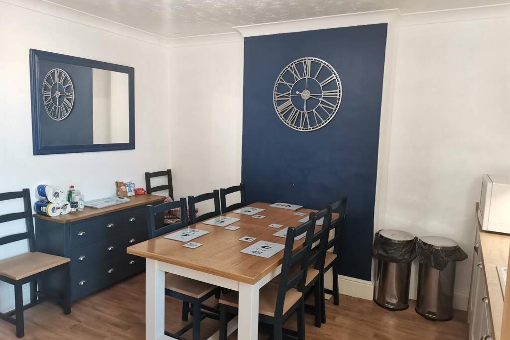 a dining room with a table and a clock on the wall at BERNARDS HIDEOUT in Cromer