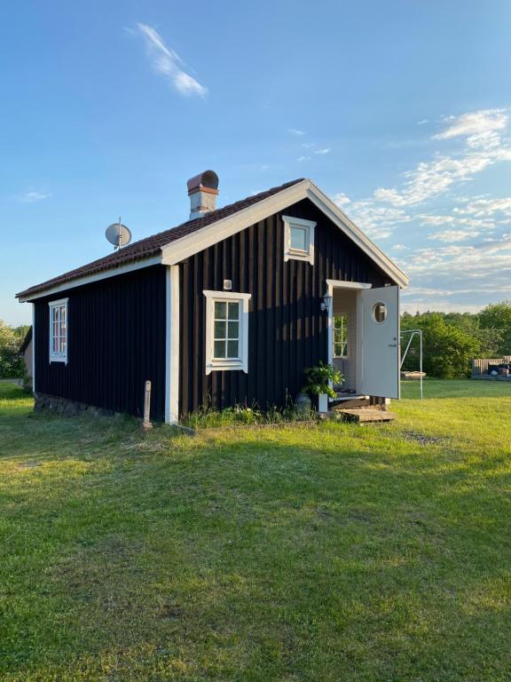ein schwarzes Haus mit einem Rasenplatz davor in der Unterkunft Lillstugan Lyckan in Kristdala